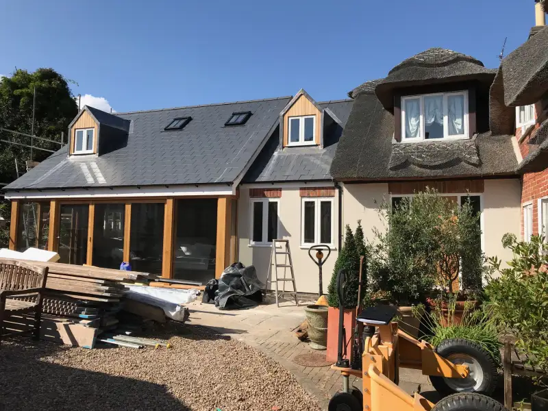 Steel clad in oak and glass two storey extension to a traditional thatched cottage in a conservation area: Swipe To View More Images